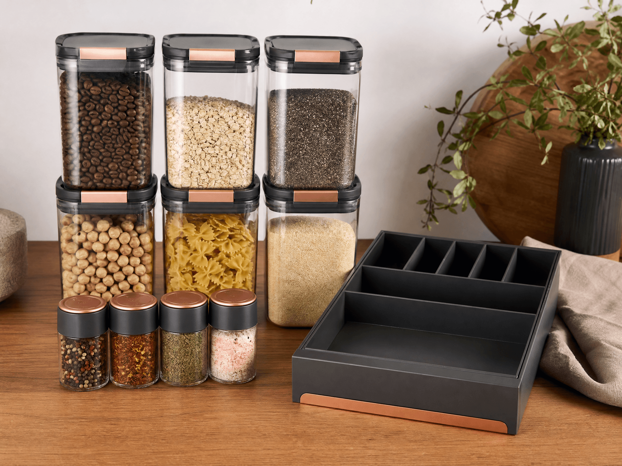 Six clear airtight containers, four spice jars and a drawer organiser on a kitchen counter